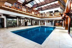 Una amplia piscina interior con terraza de madera y balcón en el segundo piso.