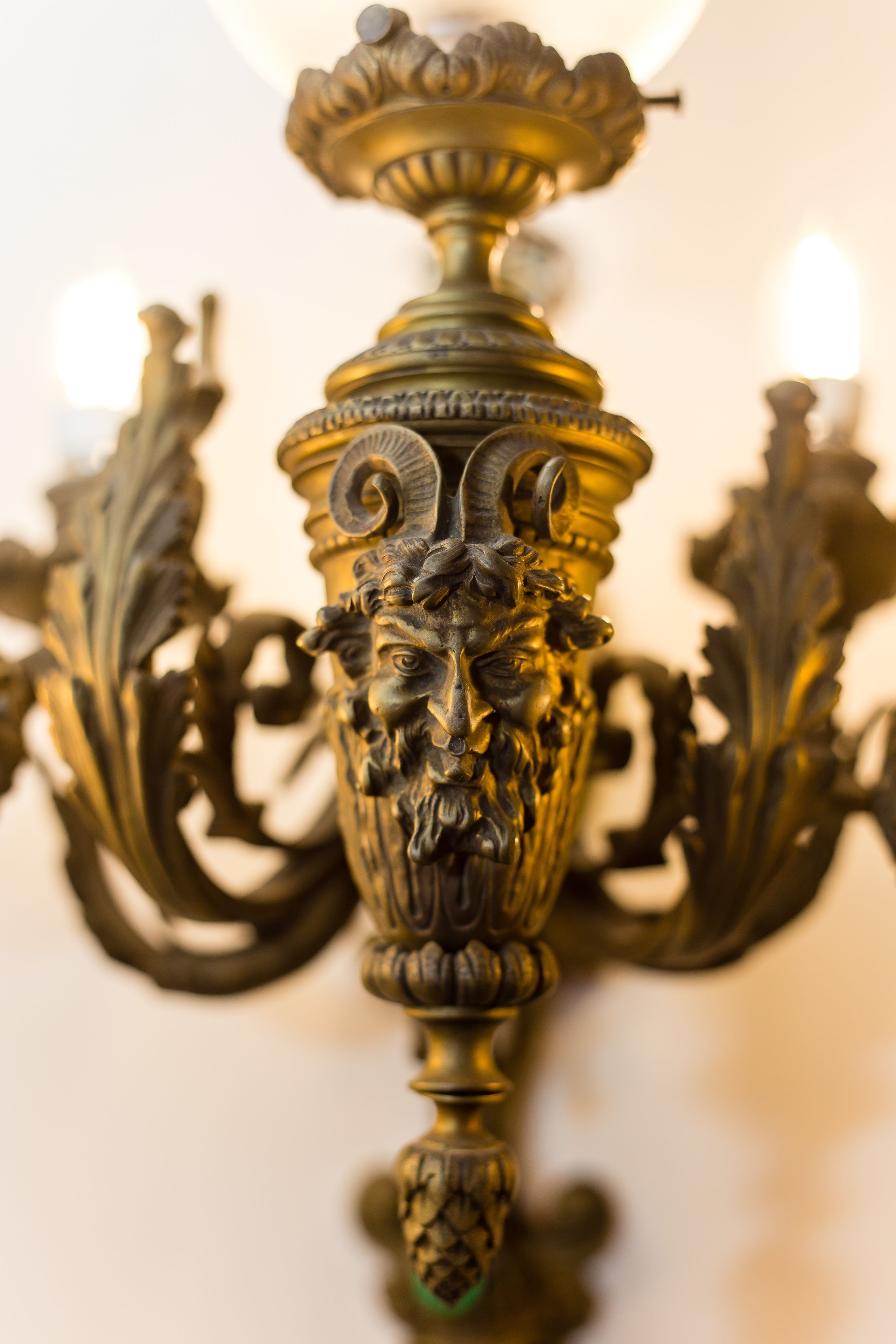 A detailed, ornate metal chandelier with intricate designs and a central bulb.