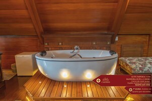 Una bañera grande y ovalada en una habitación de madera con techo alto.