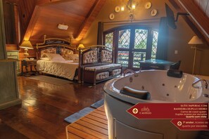 A bedroom with a large bed, a sitting area with a table and chairs, and a bathtub. There is a window with a view of greenery outside. - Hotel Castelo Nacional Inn Campos do Jordão (Campos do Jordão)