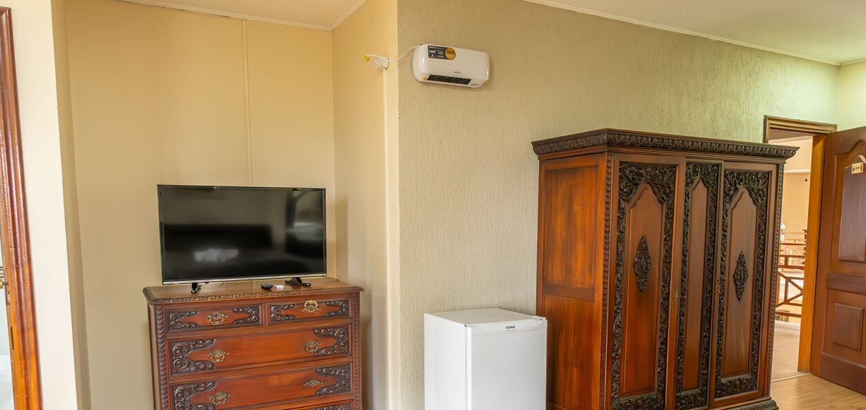 A room with a TV on a wooden dresser, a white refrigerator, and a wooden cabinet.