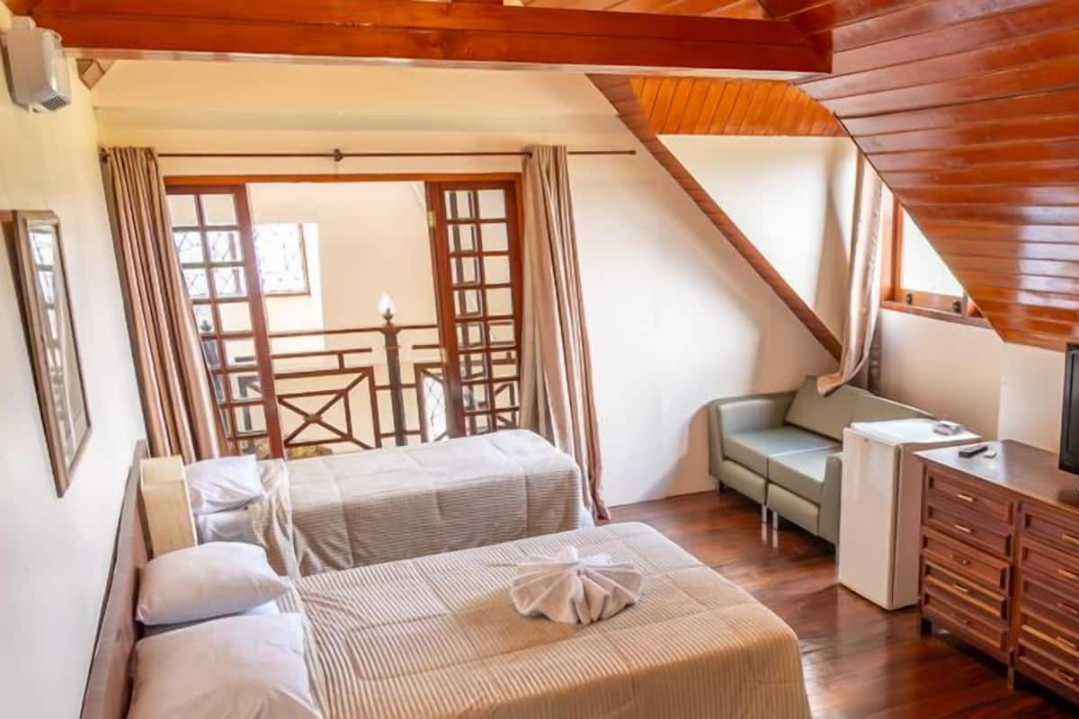 A cozy room with two beds, a sofa, a TV, and wooden cabinets.