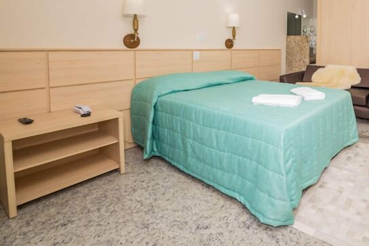 A hotel room with a bed, bedside tables, a desk, and a wardrobe.