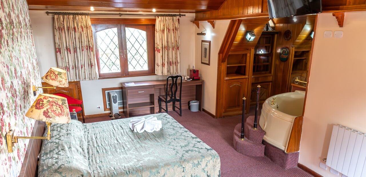Un dormitorio con cama, escritorio, silla y bañera.