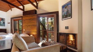 A cozy room with a fireplace, a large window, and a bed with a view of the outdoors.