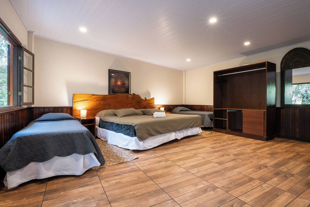 A bedroom with two beds, wooden flooring, a wardrobe, and a painting on the wall.