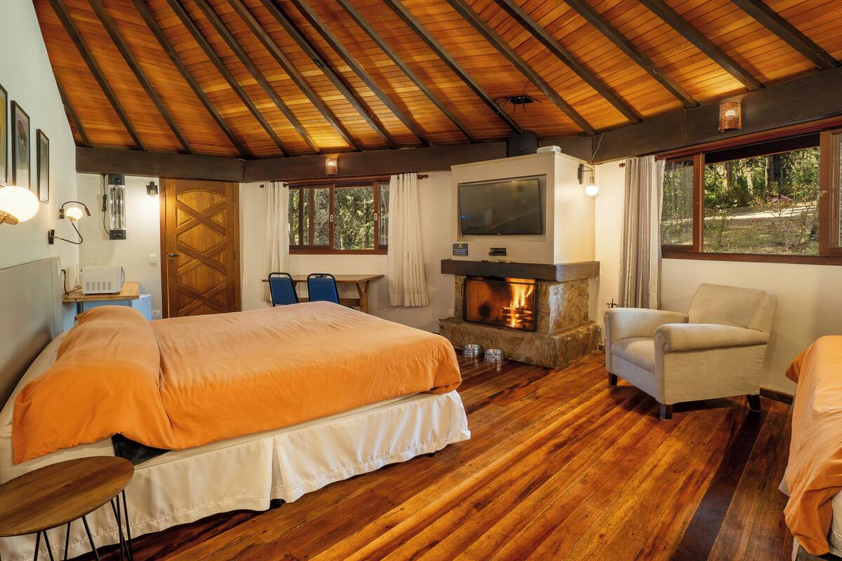 A cozy room with a bed, a chair, a fireplace, and a TV.