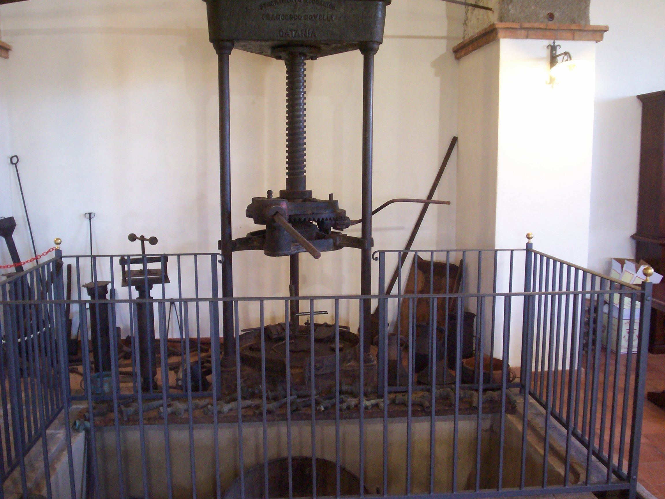 A historical mechanical press with a metal railing surrounding it.