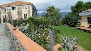 Um edifício histórico com parede de pedra e um jardim com diversas plantas e flores.