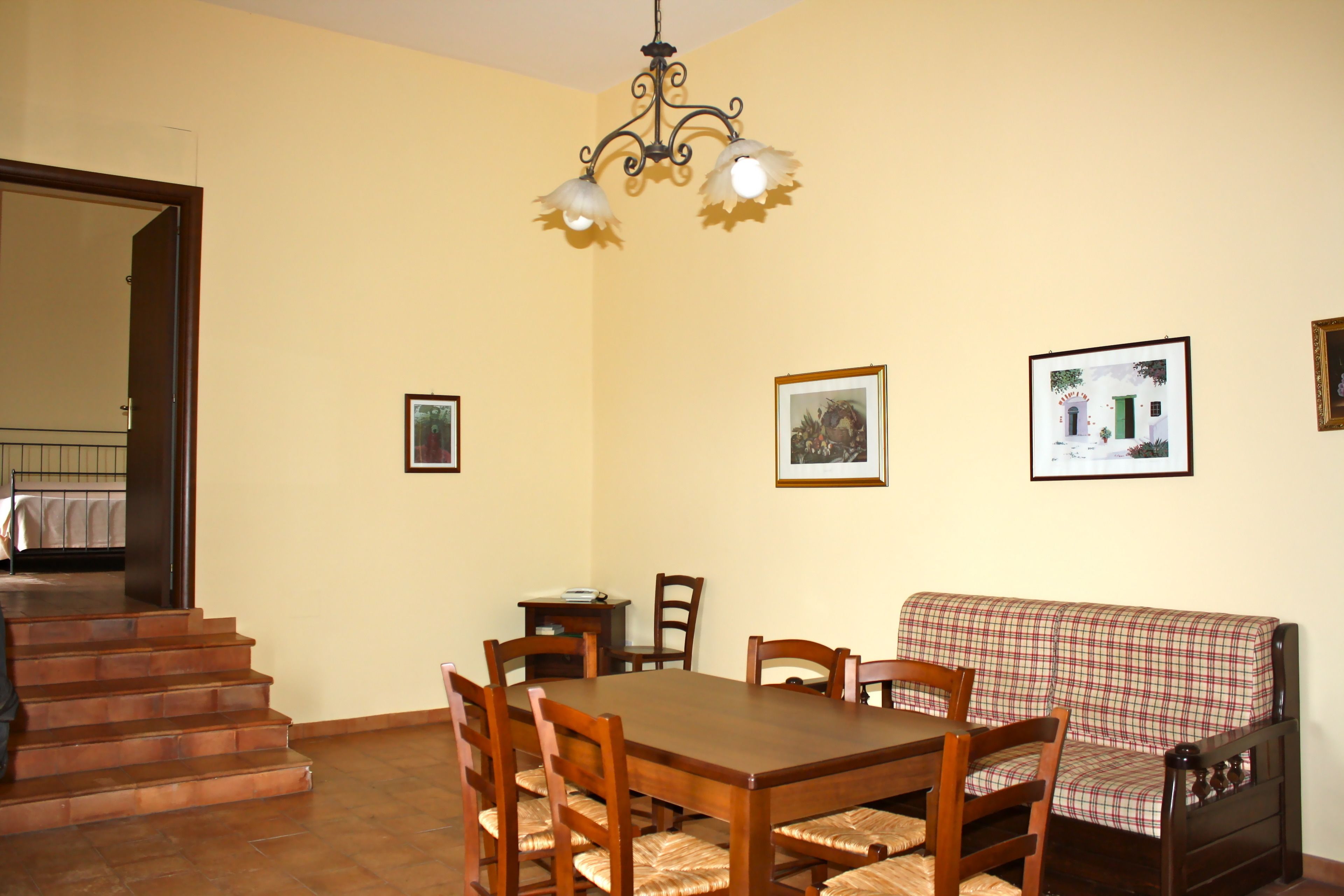 A dining area with a wooden table and chairs, a sofa, and a staircase leading to another room.