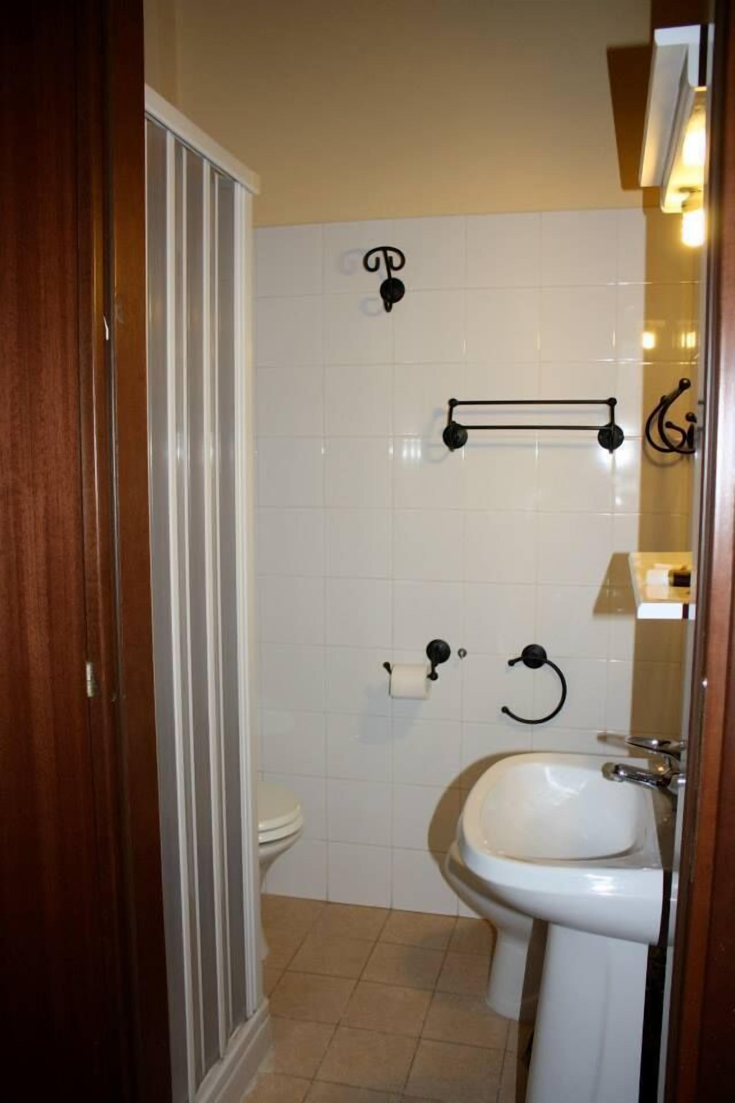 Un baño con inodoro, lavamanos y barra para toallas.
