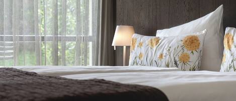 A hotel room with a bed, a lamp, and a window with curtains.