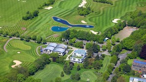 An aerial view of a golf course with sand bunkers, a pond, and a clubhouse. - GolfHotel Gut Neuenhof (Fröndenberg/Ruhr)