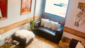 A living room with a black leather sofa, a glass coffee table, and a potted plant. - Hotel Garibaldi (Frosinone)
