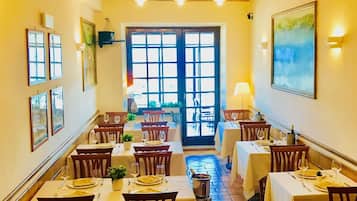 A restaurant with multiple tables, chairs, and a brick floor.