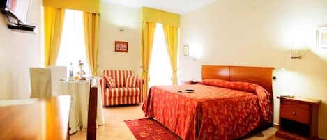 A hotel room with a bed, a sofa, a desk, and a TV.