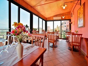 A restaurant with wooden furniture, large windows, and a view of the city. - Hotel Garibaldi (Frosinone)