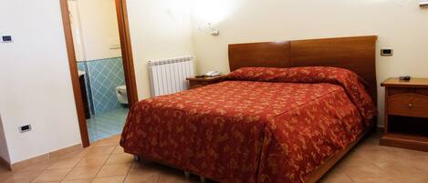 Un dormitorio con cama, mesita de noche y velador.