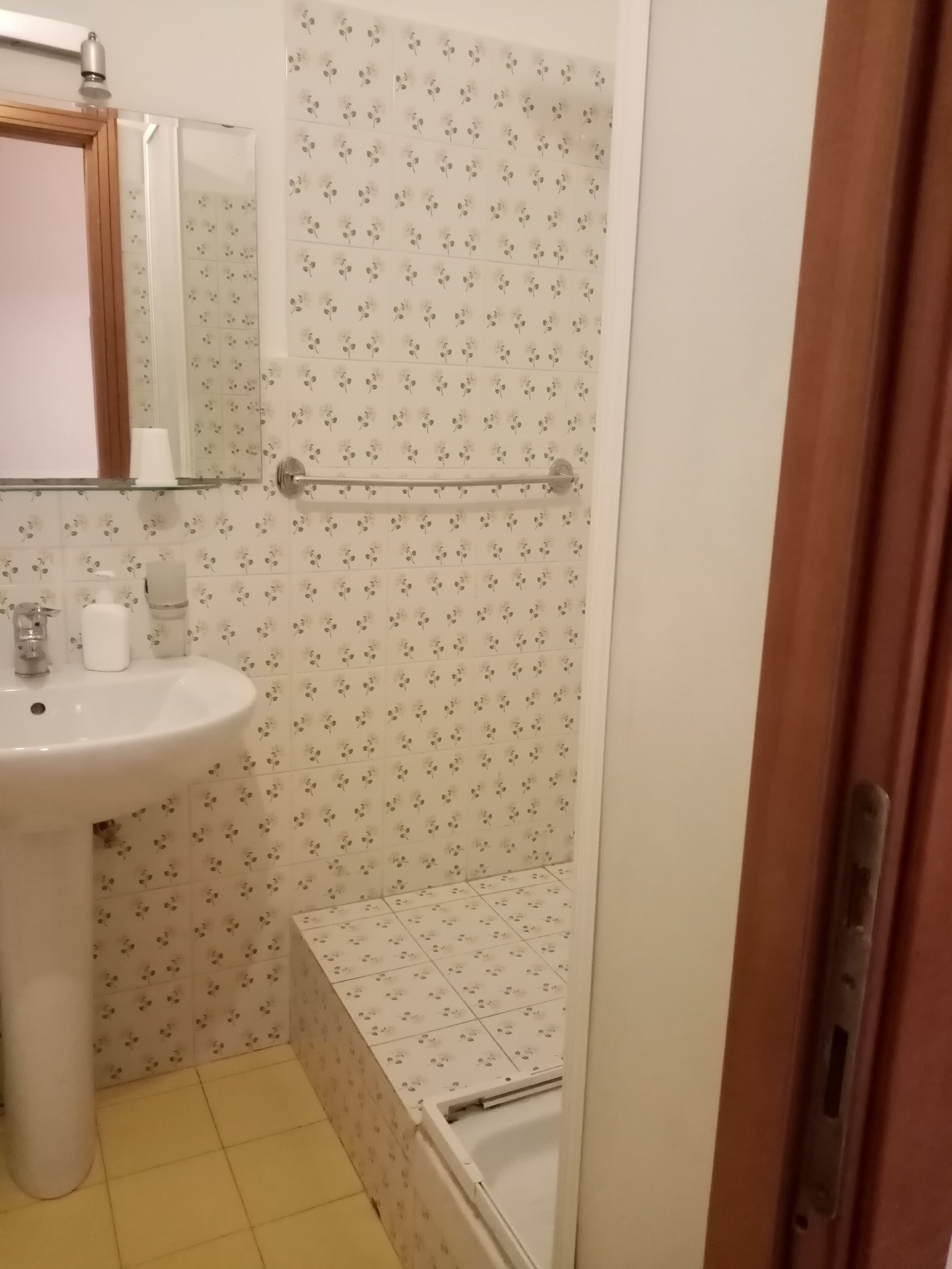A bathroom with a sink, mirror, and shower area.