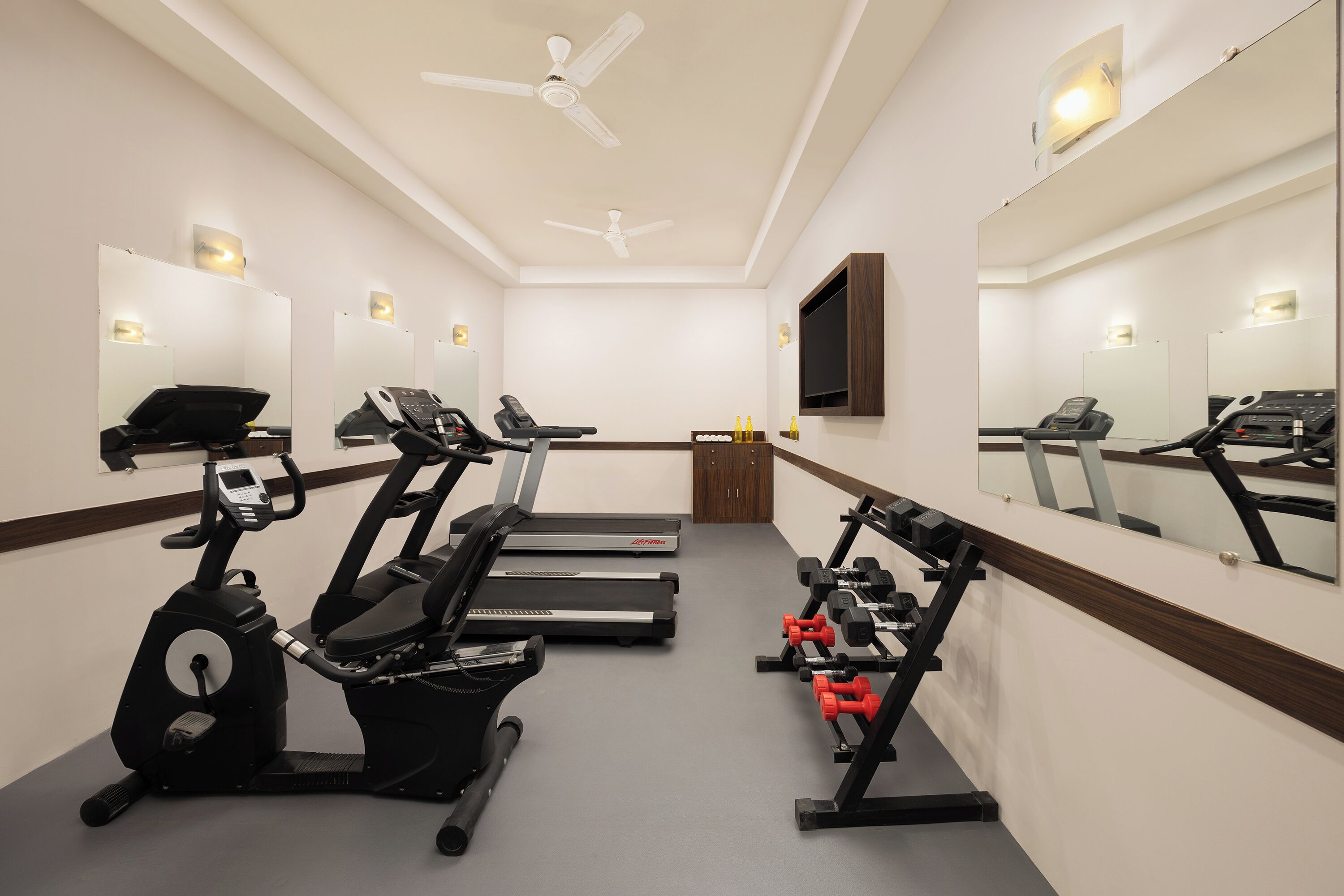 A gym with exercise equipment, a treadmill, an elliptical, and a weight bench.