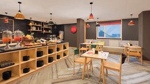 A modern cafe with wooden furniture, a fruit display, and a city view through the window. - Ginger Jaipur (Jaipur)