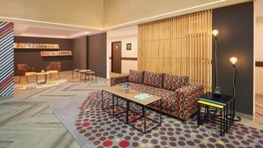 A modern lounge area with a sofa, chairs, a coffee table, and a bookshelf. - Ginger Jaipur (Jaipur)