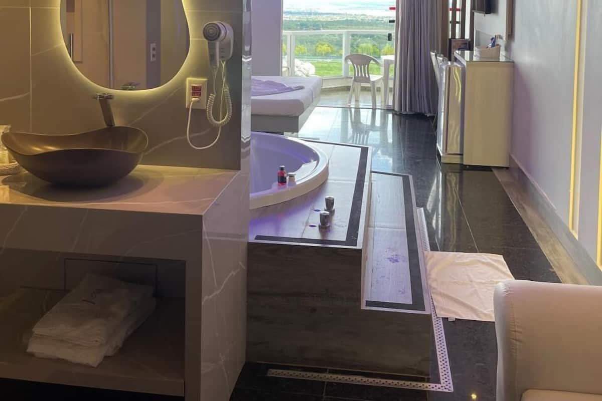 A modern bathroom with a large mirror, a bowl sink, a shower, and a bathtub.