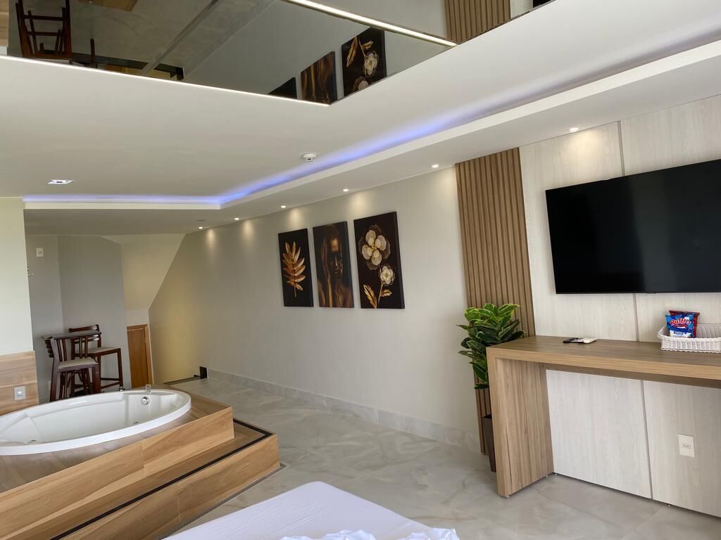 A modern bathroom with a freestanding bathtub, a wooden vanity, and a flat-screen TV mounted on the wall.