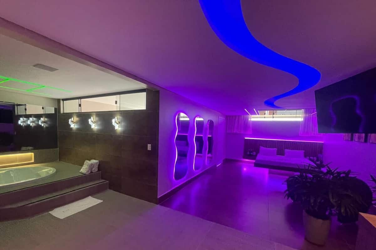 A modern bathroom with a bathtub, a vanity with a mirror, and a seating area with a plant.