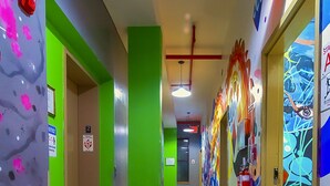 A hallway with green walls, wooden flooring, and colorful graffiti art. - NY Moore Hostel (Brooklyn)