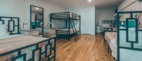 A room with bunk beds, a desk, a chair, a lamp, and a mirror.