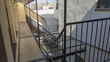 A corridor with a curved ceiling, a metal railing, and a staircase leading to an upper level.