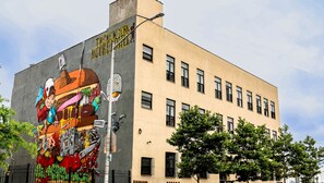 A building with a mural on the side, featuring a large burger and a cityscape. - NY Moore Hostel (Brooklyn)