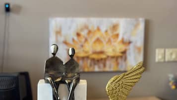 A hotel reception area with a 'QUBE HOTEL' sign, a painting of a fireplace, and two decorative items on a marble counter.
