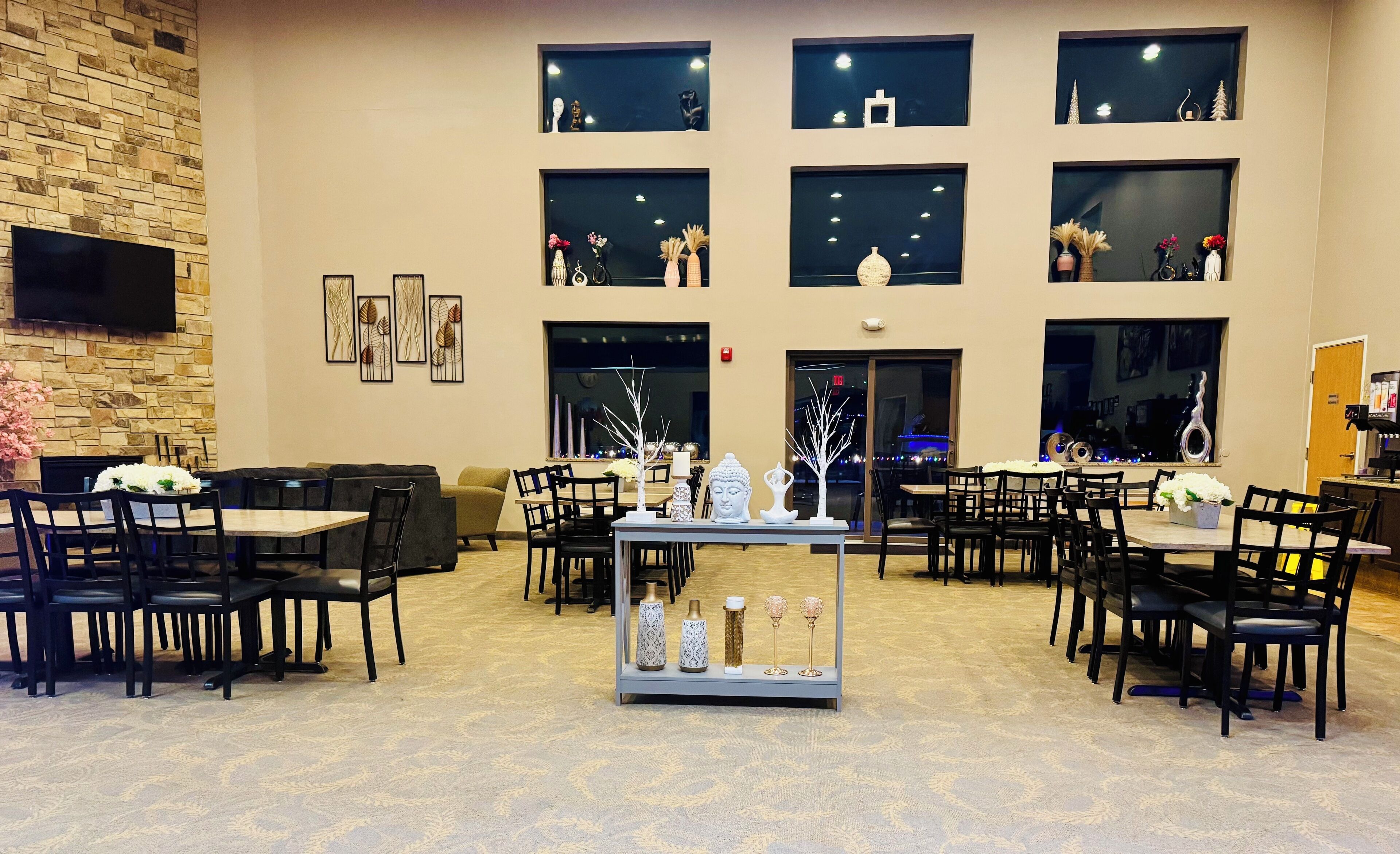 Un vestíbulo de hotel con varias zonas de estar, una exhibición central de objetos decorativos y una pared de piedra con obras de arte.