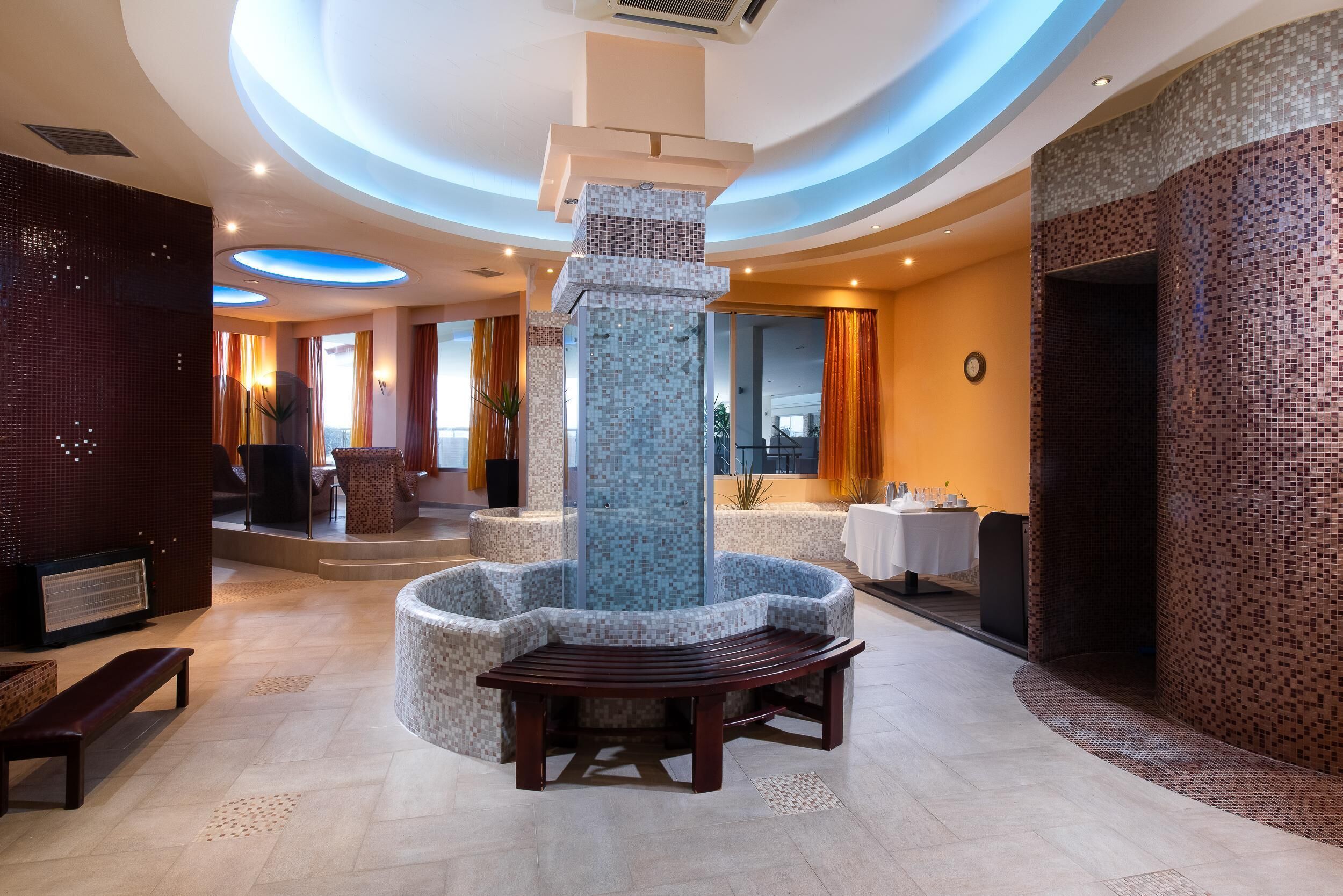 Un lobby moderno con una zona de estar central, un pilar decorativo y un muro con diseño.