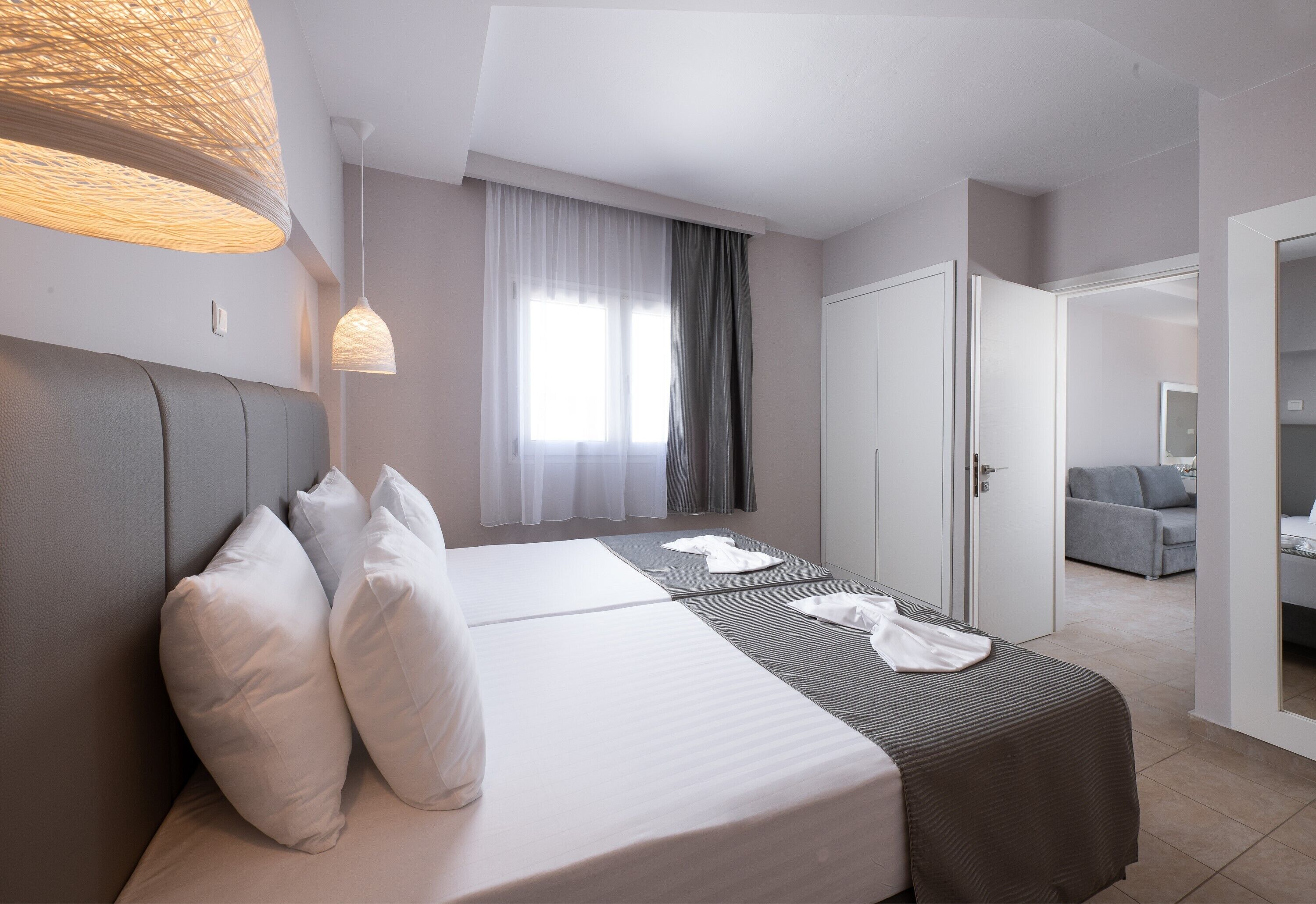 Une chambre d’hôtel avec un lit, des tables de chevet, une armoire et une vue sur une autre chambre.