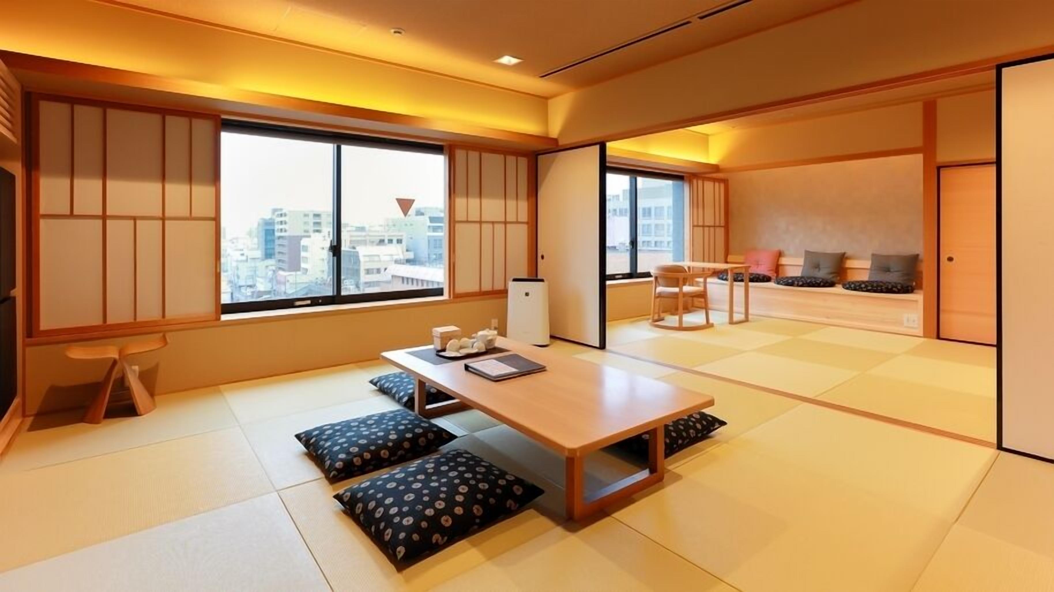 A traditional Japanese room with tatami flooring, a low table with cushions, and sliding doors.
