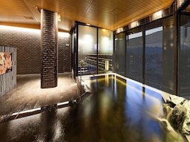 Piscina interior moderna com estrutura de vidro, teto de madeira e vista para a paisagem urbana.