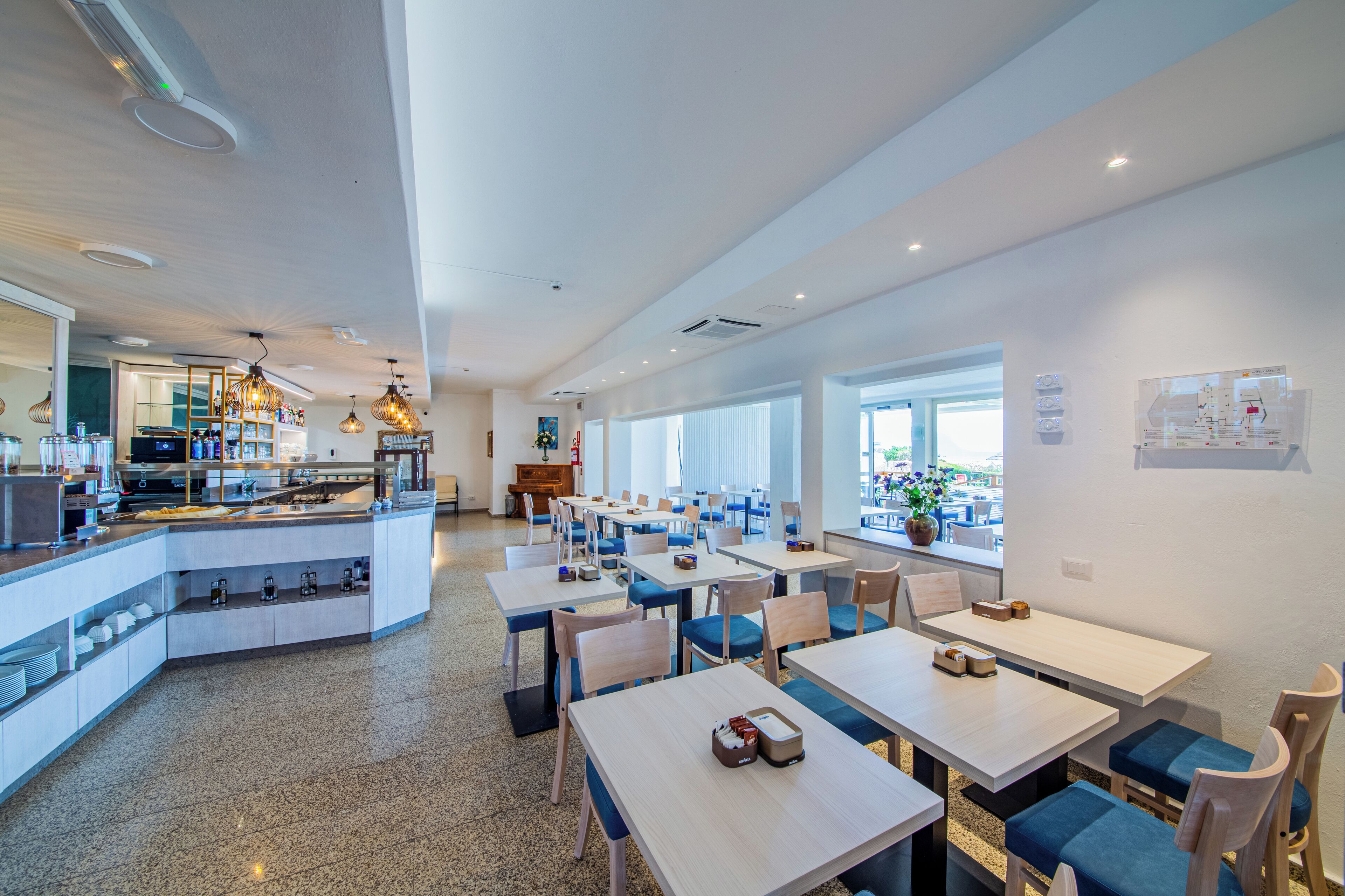 Un comedor moderno con una barra central, varias mesas y sillas.