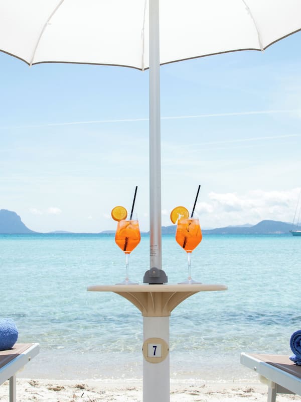 Aan een privéstrand, wit zand, ligstoelen, parasols