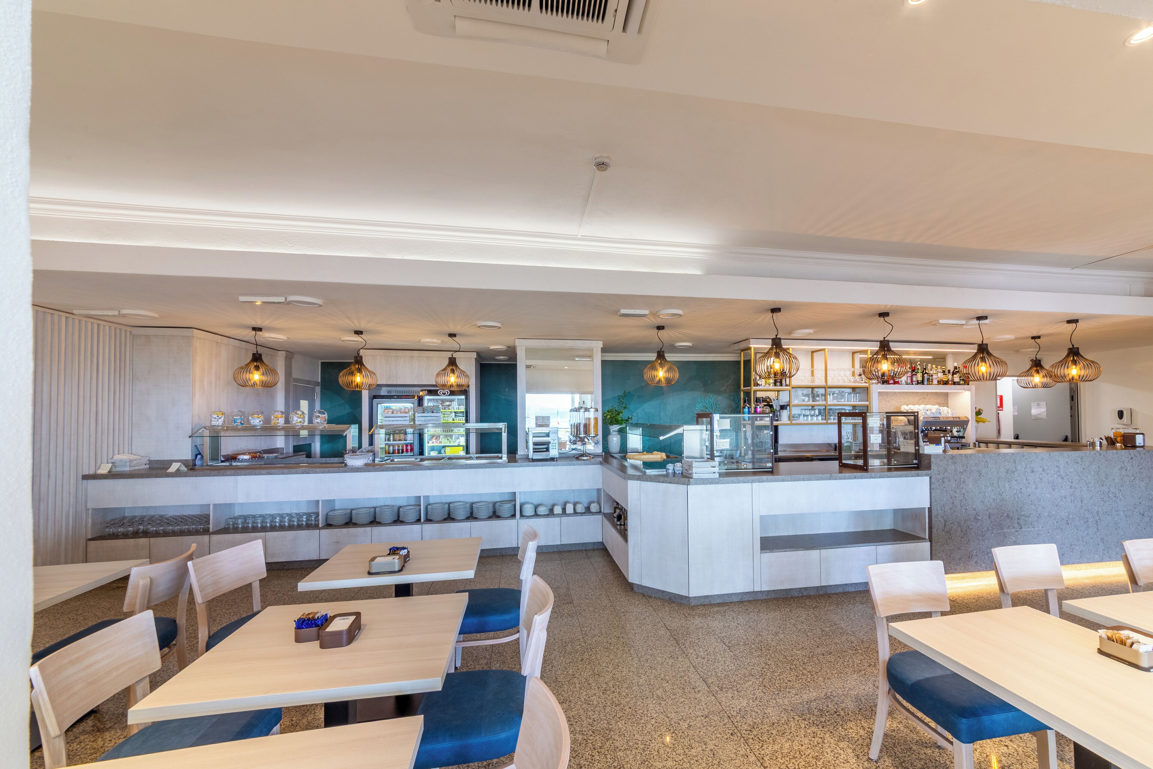 A modern restaurant with a central counter, seating area, and a bar.