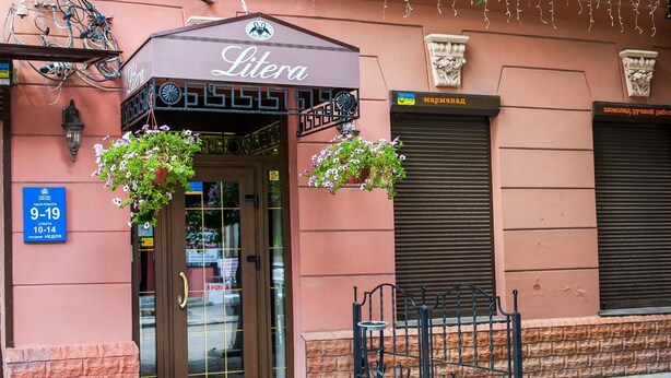 A building entrance with a sign reading "Litera" and a sign indicating a business hours of 9-19. - Hotel Litera (Dnipro)