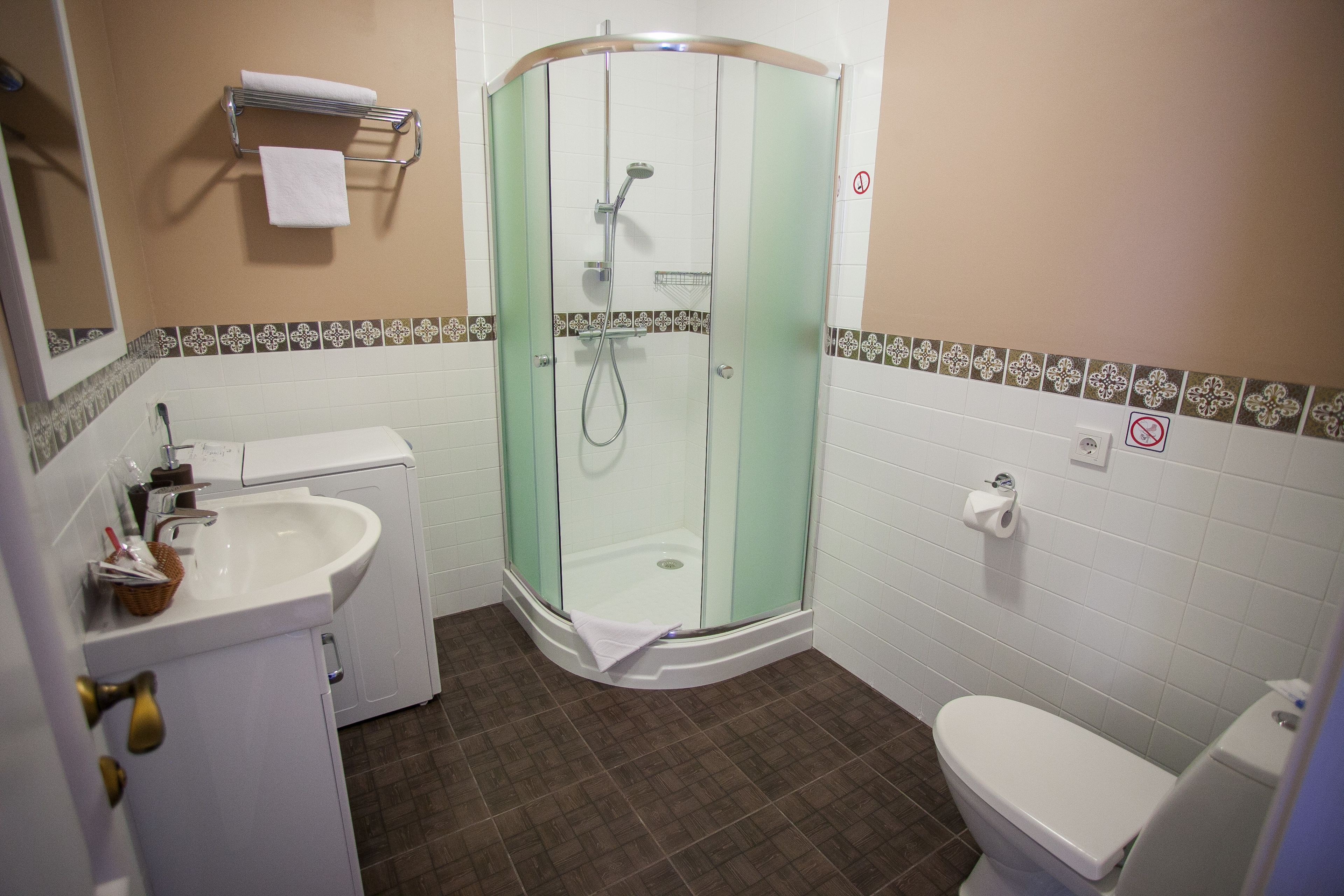 A bathroom with a glass-enclosed shower, a white sink, a toilet, and a towel rack.