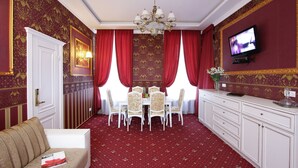 A dining area with a chandelier, red curtains, a television, and a white cabinet. - Hotel Litera (Dnipro)