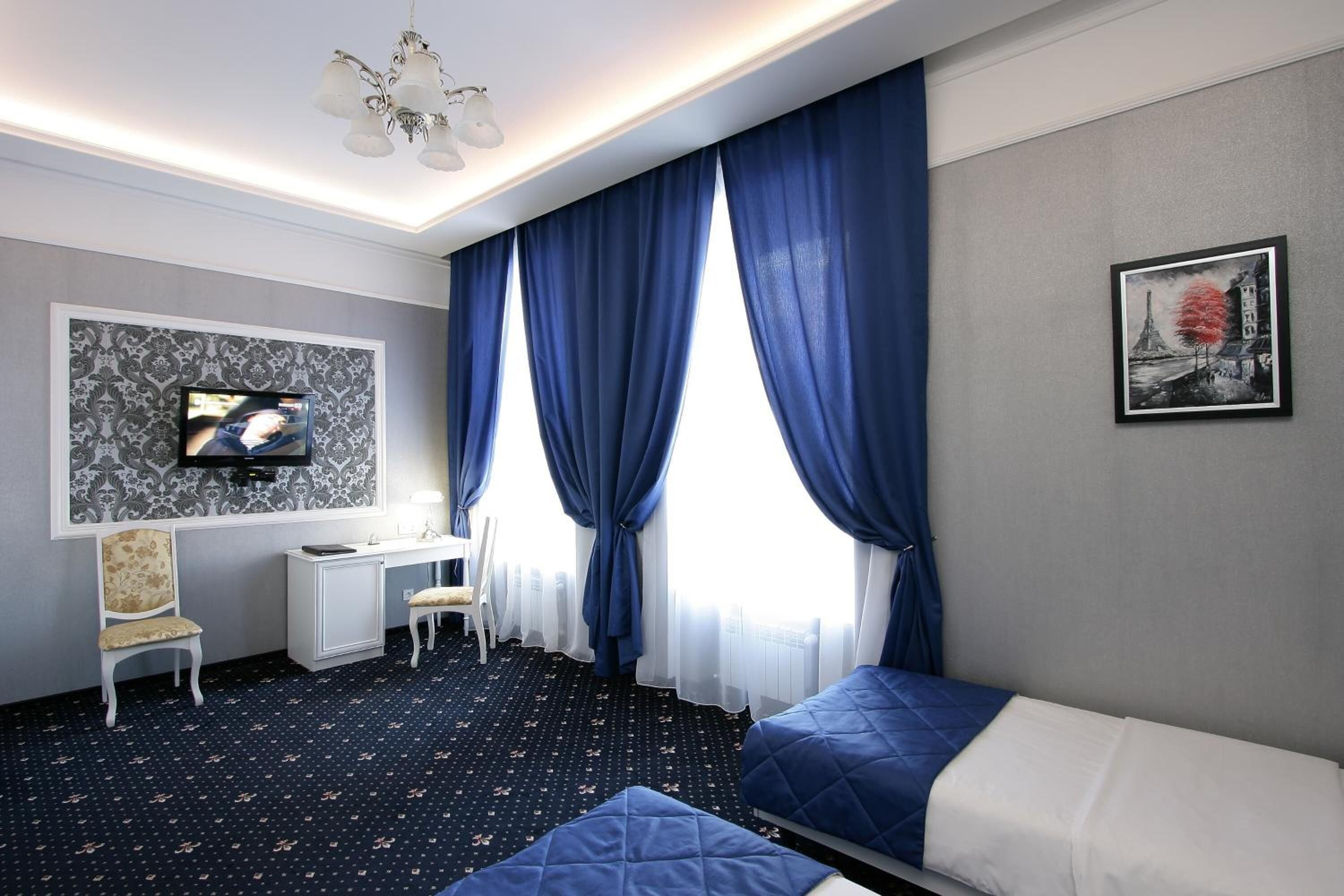 Una habitación de hotel con dos camas, un escritorio, una silla y un televisor.