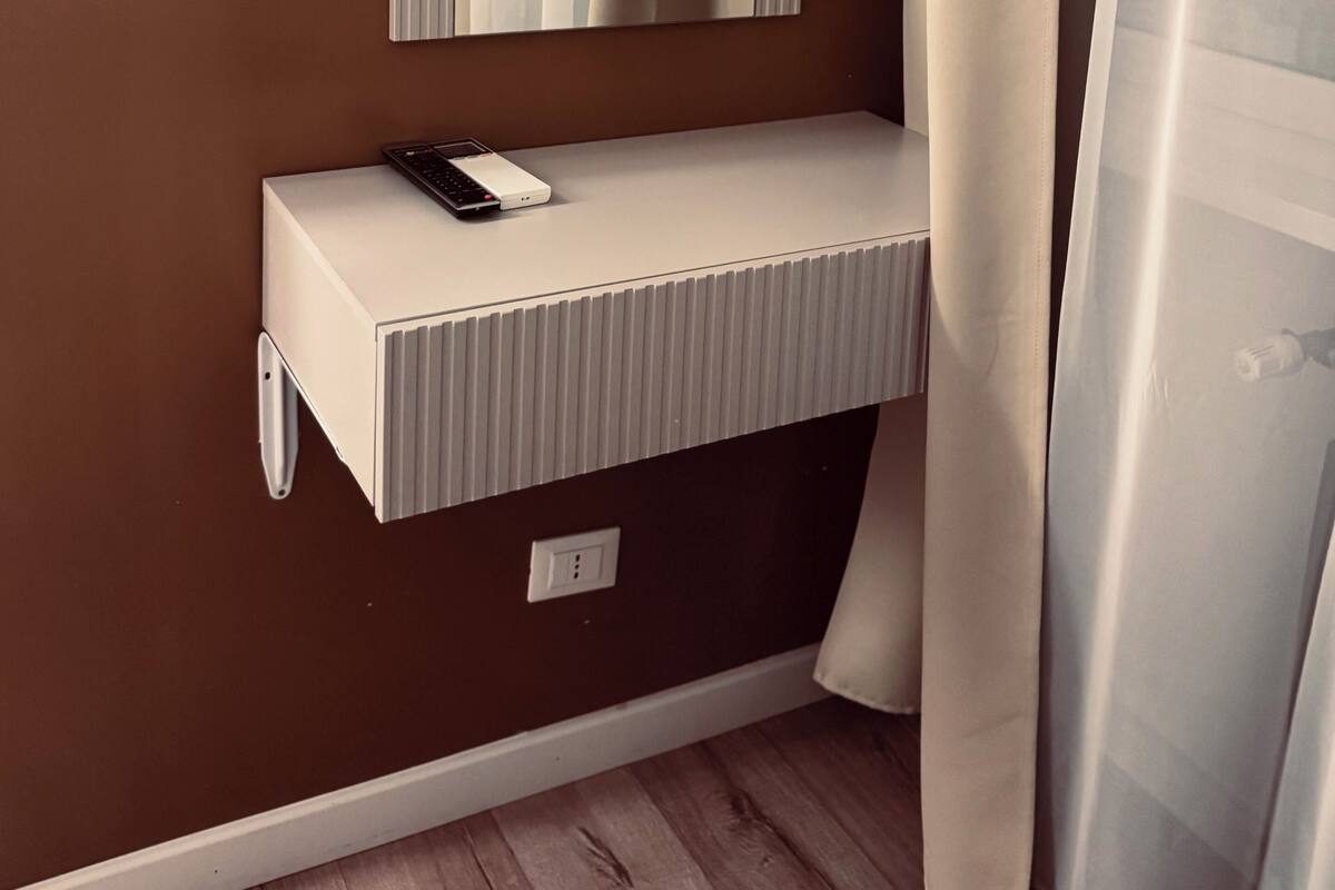 Un baño moderno con un tocador blanco, un espejo y un enchufe.