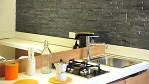 A modern kitchen with a stone backsplash, wooden countertop, and hanging glass bottles. - B&B Living (Rome)