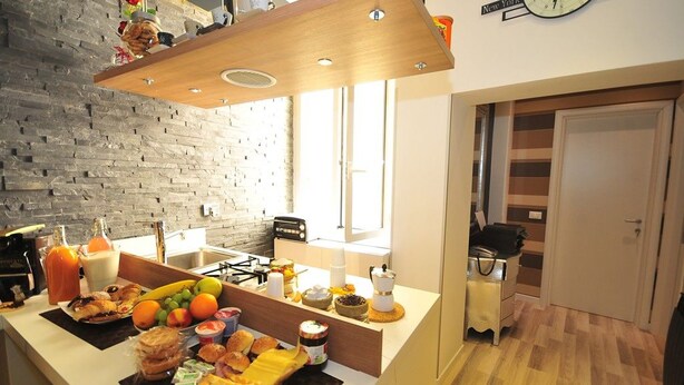 A modern kitchen with a brick wall, wooden countertop, and a clock on the wall. - B&B Living (Rome)