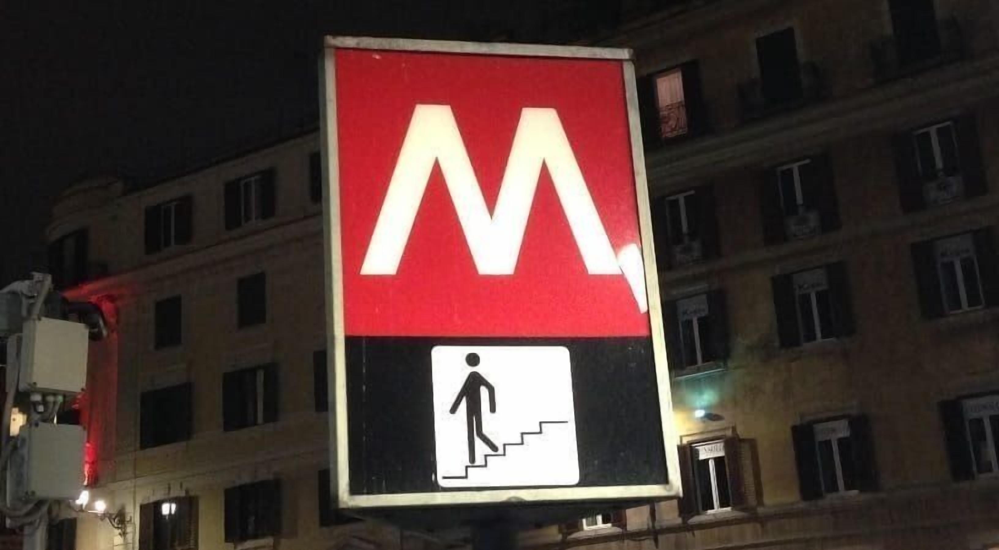 A pedestrian crossing sign with a large 'M' and a symbol of a person walking on stairs.